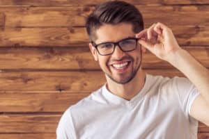 handsome young man in eyeglasses looking at camera and smiling 300x200 1