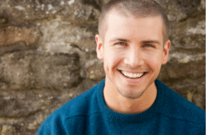 Attractive young man sitting, smiling outside