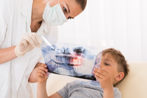 Young Female Doctor Showing Teeth Xray To Child Patient In Clinic