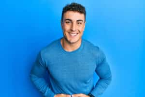 Hispanic young man wearing casual winter sweater smiling