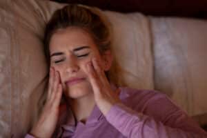 Girl holding her jaw and face in pain from TMJ