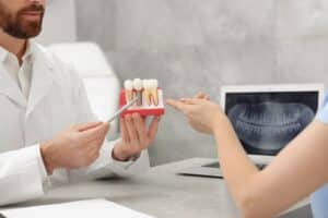 Dentist explaining dental implants, crowns, and bridges to patient