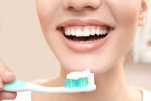 Close-up of a smiling woman brushing her teeth, showing healthy gums and beautiful teeth