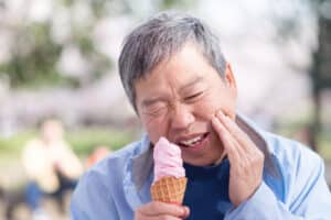 Man eating ice cream and experiencing pain in sensitive teeth