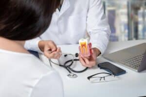 Doctor showing a woman a model of a tooth and explaining how a root canal works.