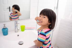 Little girl smiling and brushing her teeth