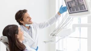 Dentist showing a patient digital dental X-rays during a tooth replacement consultation in Mesa, AZ.